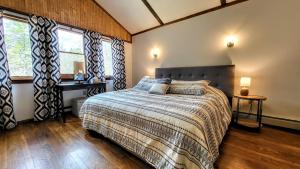 The Wooden Nest by AvantStay Deck Big Yard w Hammocks Fire Pit في Long Pond: غرفة نوم بها سرير ومكتب ونوافذ