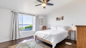 a white bedroom with a bed and a large window at Saratoga by the Sea by AvantStay Panoramic View Near Langley in Langley