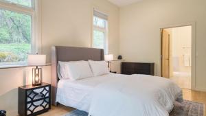 a bedroom with a white bed and two windows at Secluded Modern Enclosed Patio Forest Views Woodland Zen by AvantStay in Stockbridge