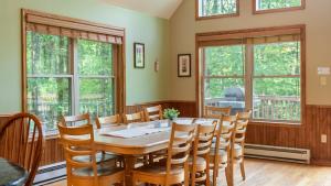 Un comedor con mesa y sillas y ventanas. en Coyote Cabin by AvantStay Hot Tub Walk to Lake, en Lake Harmony