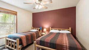 2 camas en una habitación con ventilador de techo y ventana en Coyote Cabin by AvantStay Hot Tub Walk to Lake, en Lake Harmony