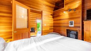 Penn Cove Overlook by AvantStay Cabin w Views في أوك هاربور: غرفة نوم بجدران خشبية وسرير ومدفأة