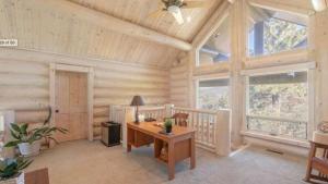 Una oficina en una casa de troncos con escritorio y ventanas. en Hot Tub Game Room Large Deck w Incredible View Penticton Lodge by AvantStay, en Big Bear Lake