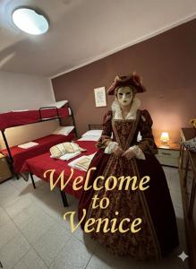 a woman in a dress standing next to a bed at Admiral Home Venice Center in Venice