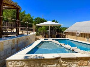 a swimming pool with an umbrella next to a house at HILLSIDE in Concan