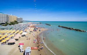 een druk strand met mensen en parasols in het water bij Stella Marina in Montesilvano