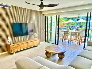 Lagoon Swimout Absolute Pool Front - Tropical Paradise -in Sea Temple Pt Douglas في ميناء دوغلاس: غرفة معيشة مع أريكة وتلفزيون وطاولة