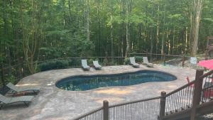 einen Pool mit Stühlen, einem Zaun und Bäumen in der Unterkunft Misty Mountain by AvantStay Hot Tub Mountain Views Theater Pool Table in Gatlinburg