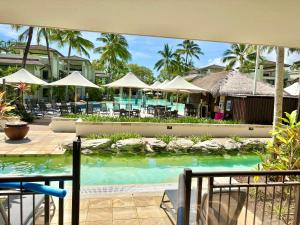 Lagoon Swimout Absolute Pool Front - Tropical Paradise -in Sea Temple Pt Douglas في ميناء دوغلاس: مسبح في منتجع به طاولات ومظلات