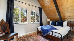 a bedroom with a bed and two windows at Hot Tub Fire Pit Deck Views Near the Lake The Matterhorn Manor by AvantStay in Crestline