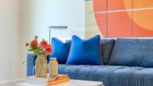 a blue couch with a vase of flowers on a table at Carter 202 by AvantStay 1BR Balcony in Nashville