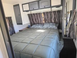 a bedroom with a bed with blue comforter at Clamping Caravan in Whanganui