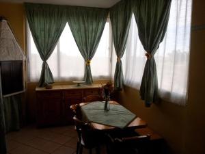 ein Esszimmer mit einem Tisch und 2 Fenstern in der Unterkunft Appartamento Angela in Margherita di Savoia