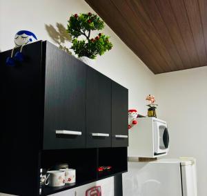a kitchen with black cabinets and a microwave and a refrigerator at Hospedagem Marechal 03 in São Roque