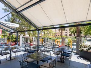 un patio al aire libre con mesas, sillas y ventanas en Mercure Perth On Hay, en Perth