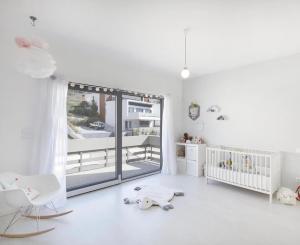 een witte kamer met een babybedje en een raam bij Jardins da Parede Villa in Parede +12 foto's