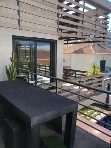 een terras met een zwarte tafel en een balkon bij Jardins da Parede Villa in Parede