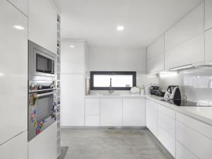 a white kitchen with white cabinets and a window at Jardins da Parede Villa in Parede