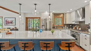 Waterside Haven by AvantStay Lakefront Hot Tub Game Room Fire Pit في Long Pond: مطبخ فيه دواليب بيضاء وجزيرة كبيرة فيها كراسي