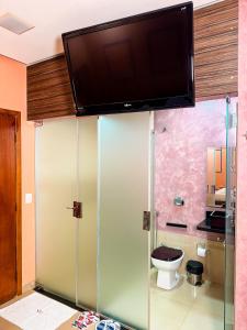 een badkamer met een toilet en een tv aan de muur bij Rodotel Vênus Prime in Acreúna