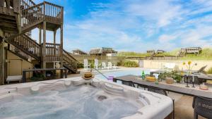 Sleeps 28 Beachfront w Pool Hot Tub Game Room Atlantic Watch by AvantStay في كيل ديفيل هيلز: حوض استحمام ساخن على فناء بجوار حمام سباحة