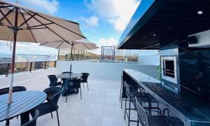 a patio with tables and chairs and an umbrella at Comfort and elegance in the heart of Cabo Branco in João Pessoa