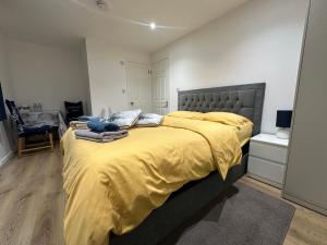 a bedroom with a large bed with a yellow blanket at L-Houses in Dagenham