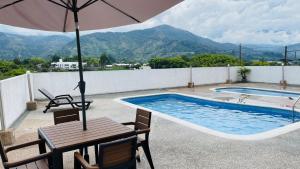 a table with an umbrella next to a swimming pool at Refugio de la cordillera in Armenia
