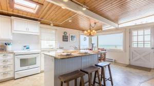 a kitchen with white cabinets and a island with stools at West Beach Wonderland by AvantStay Waterfront in Oak Harbor