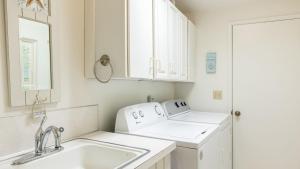 a white kitchen with a sink and a washing machine at West Beach Wonderland by AvantStay Waterfront in Oak Harbor +31 photos
