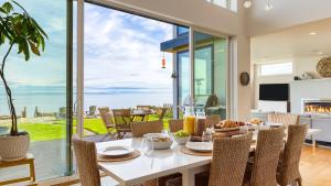 a dining room with a table and chairs and a large window at Chic Whidbey Island Waterfront Home w Hot Tub Firepits Views in Coupeville