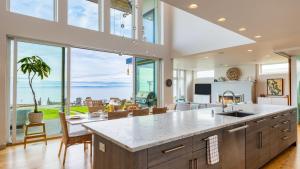 a kitchen with a large island and a large window at Chic Whidbey Island Waterfront Home w Hot Tub Firepits Views in Coupeville