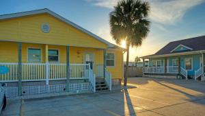 a yellow house with a palm tree in front of it at Stylish 2BR Coastal Getaway w Pool Prime Location Lazy Fun in Port Aransas