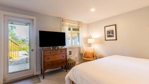 a bedroom with a bed and a flat screen tv at Mid-Century Beach Cabin by AvantStay Walk to Beach in Coupeville