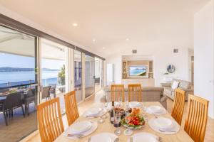 a dining room and living room with a table and chairs at Wanda Beach Waterfront , 161 Soldiers Point Rd - waterfront, air con, linen, Wi-Fi in Salamander Bay