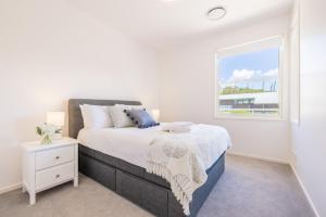 a white bedroom with a bed and a window at Wanda Beach Waterfront , 161 Soldiers Point Rd - waterfront, air con, linen, Wi-Fi in Salamander Bay