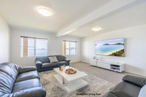 a living room with a couch and a tv at Wanda Beach Waterfront , 161 Soldiers Point Rd - waterfront, air con, linen, Wi-Fi in Salamander Bay