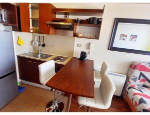 a small kitchen with a wooden table and white chairs at Metroapart 1 in Santiago