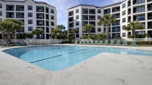 a large swimming pool in front of two apartment buildings at 308 Summerhouse by AvantStay Oceanview Condo w Community Pool Access in Isle of Palms