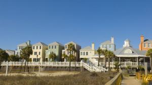 a row of houses on the beach with palm trees at 308 Summerhouse by AvantStay Oceanview Condo w Community Pool Access in Isle of Palms