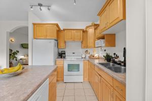 a kitchen with wooden cabinets and white appliances at Stylish 3-Bedroom Home in Buena Vista in Saskatoon
