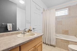 a bathroom with a sink and a tub and a toilet at Stylish 3-Bedroom Home in Buena Vista in Saskatoon +26 photos