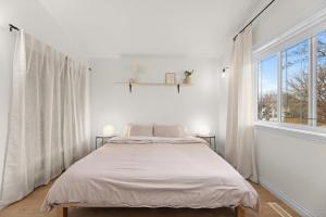 a white bedroom with a bed and a large window at Stylish 3-Bedroom Home in Buena Vista in Saskatoon