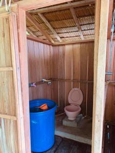 a bathroom with a toilet and a blue trash can at Miguel Homestay in Besir