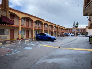 Vip Inn Motel في Cudahy: سيارة زرقاء متوقفة في موقف للسيارات أمام مبنى