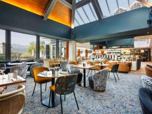 a restaurant with tables and chairs and windows at Le Saint Gervais Hotel & Spa Handwritten Collection in Saint-Gervais-les-Bains