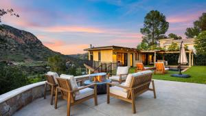 Designer Retreat w Pool Firepits Panoramic Views The Lake House at Malibu في أغورا هيلز: فناء مع كراسي وطاولة ومنزل