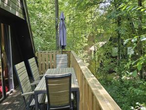 um deck de madeira com três cadeiras e um guarda-sol em Peaceful Ardennes Getaway for 4 Guests em Septon