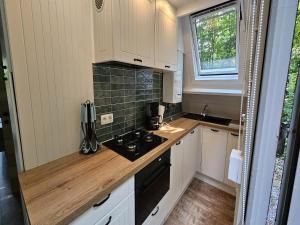 cocina pequeña con armarios blancos y fogones en Peaceful Forest Chalet near Durbuy, en Septon 3 fotos más