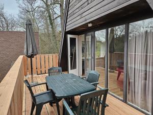 um pátio com uma mesa, cadeiras e um guarda-sol em Warm Countryside Haven in Durbuy em Septon